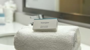 A stack of white towels on a bathroom counter with a Neutrogena® bath soap box on top.