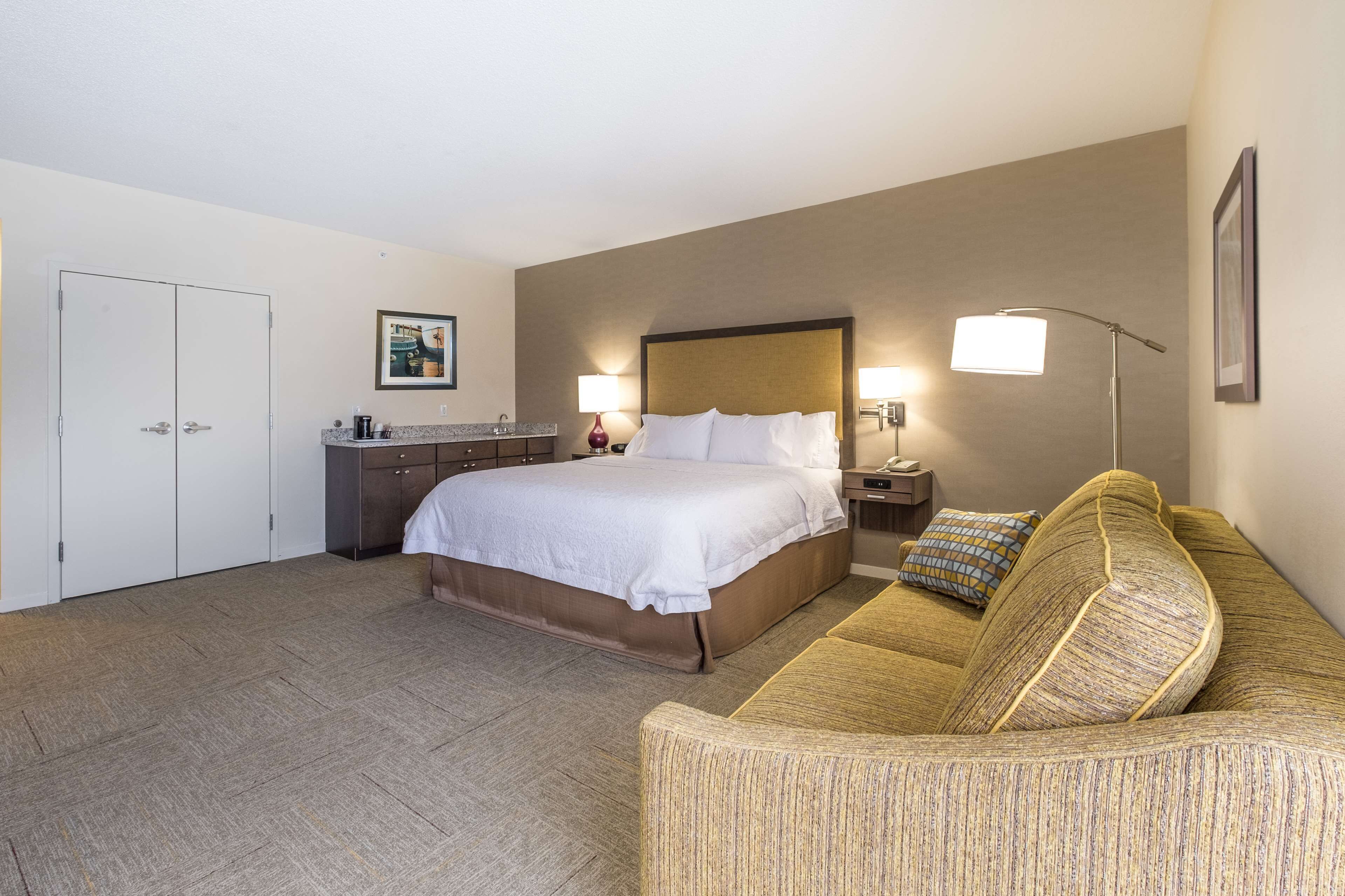 A hotel room with a bed, a sofa, a desk, and a wardrobe.