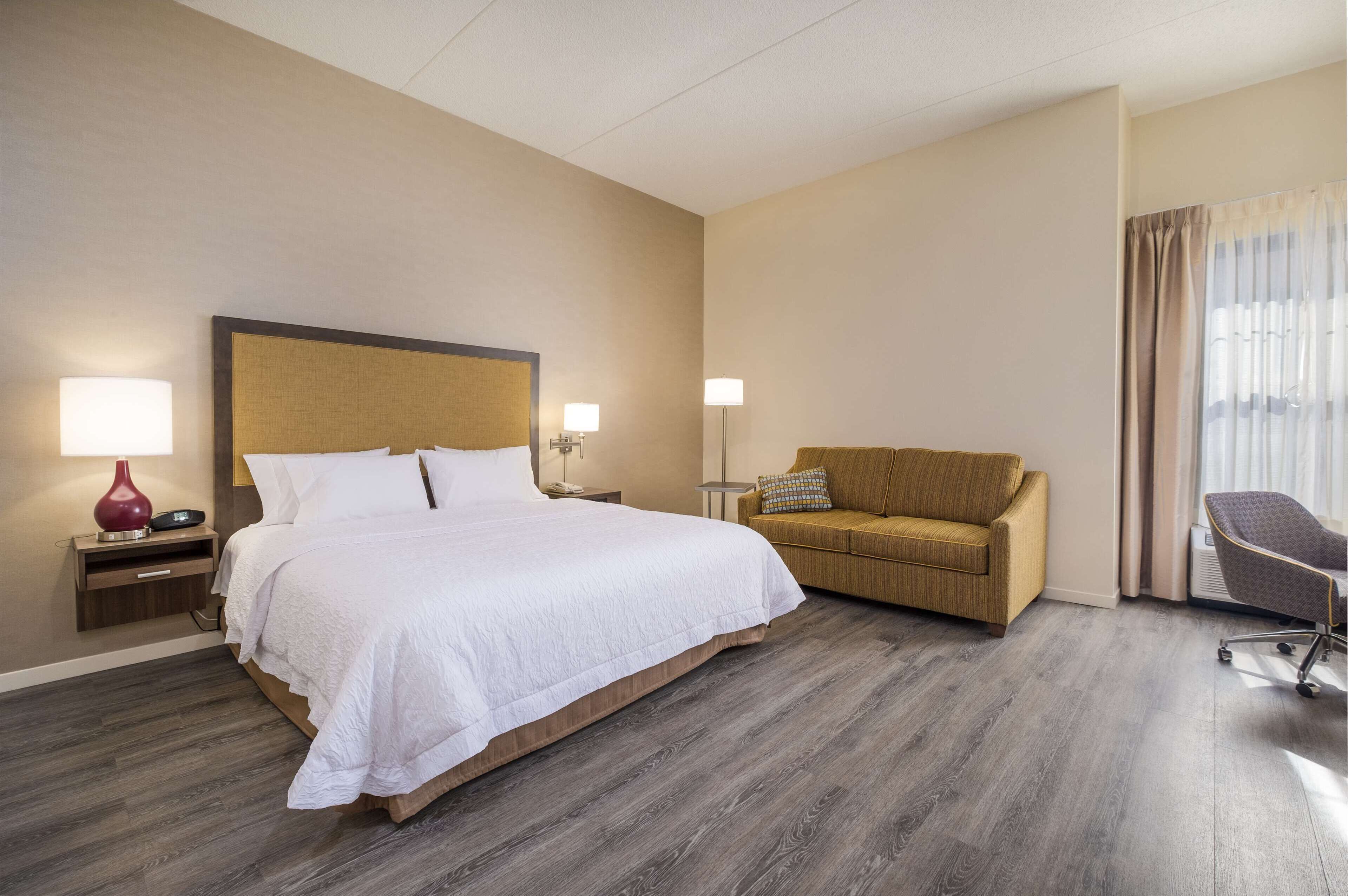 A hotel room with a large bed, a sofa, a desk, and a chair.