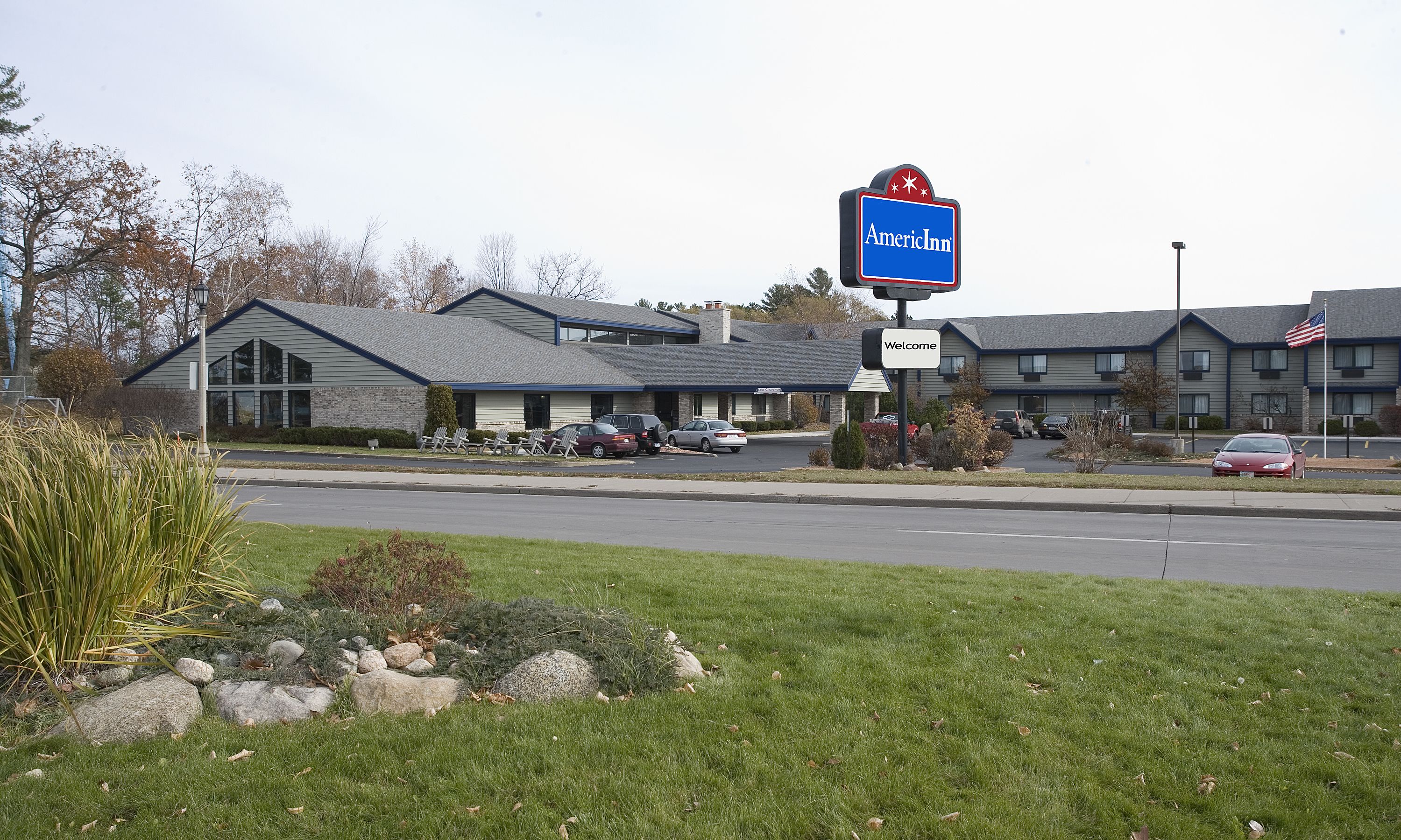 A motel with a blue sign, a welcome sign, and an American flag.