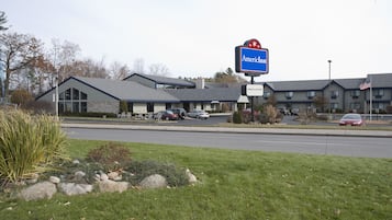 A motel with a blue sign, a welcome sign, and an American flag.