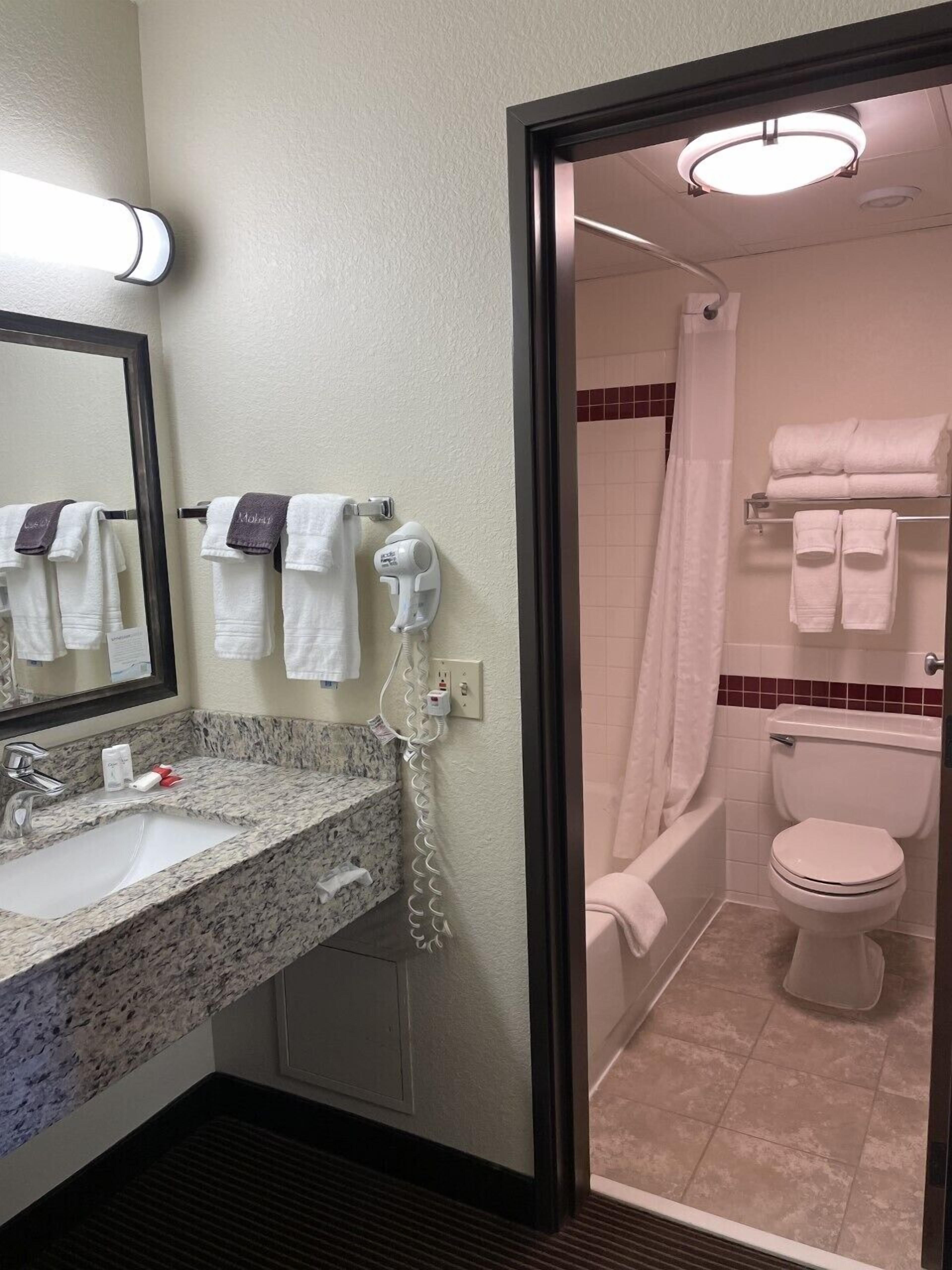 A bathroom with a sink, mirror, towel rack, and a shower area.