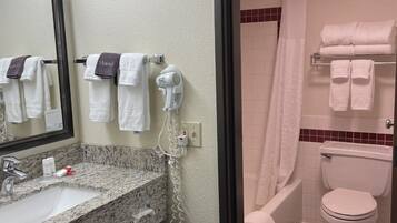 A bathroom with a sink, mirror, towel rack, and a shower area.