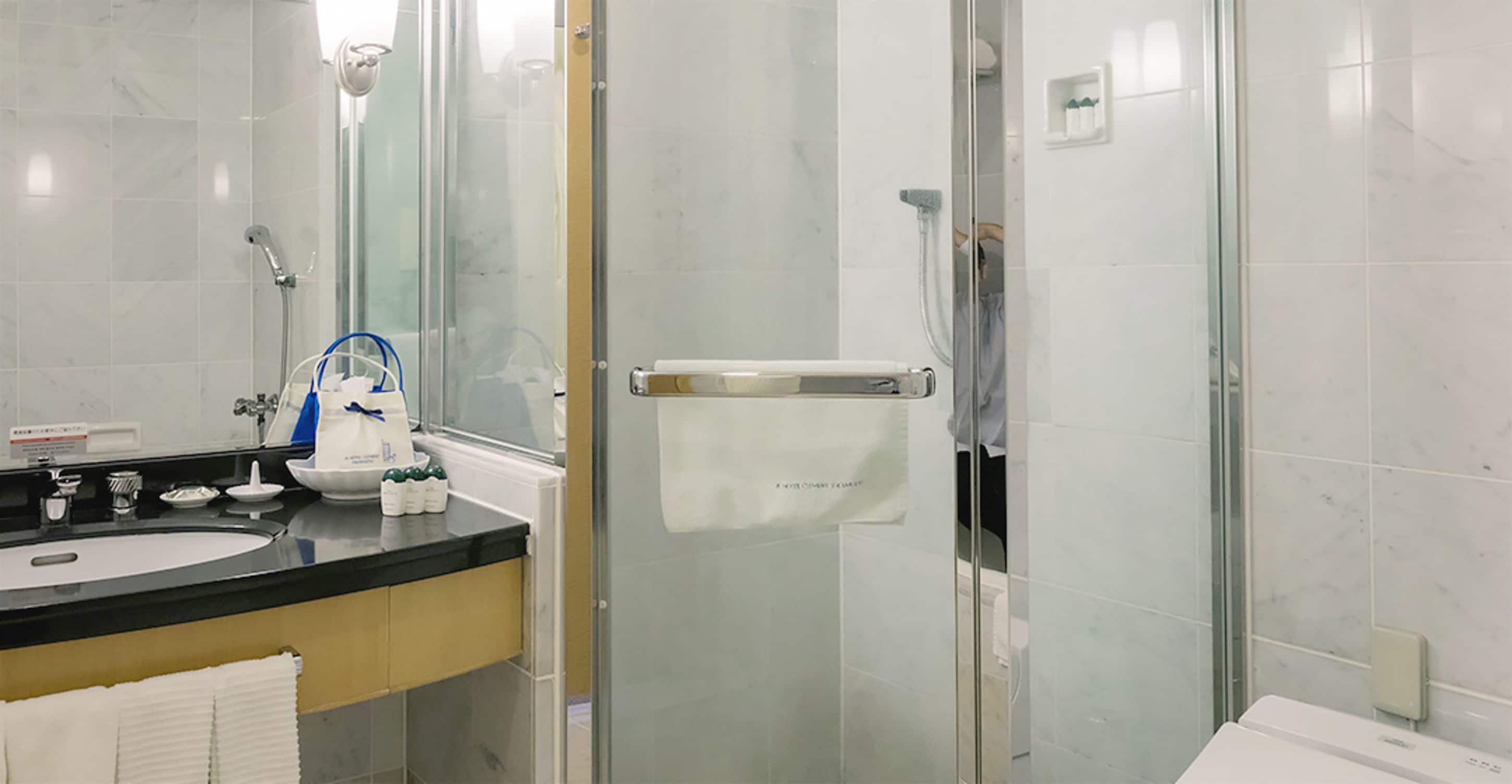 Un baño moderno con ducha de vidrio, lavamanos con espejo e inodoro.
