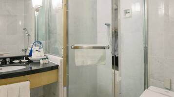 Un baño moderno con ducha de vidrio, lavamanos con espejo e inodoro.
