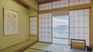 Una habitación japonesa tradicional con suelo de tatami, biombos shoji y vista al mar.