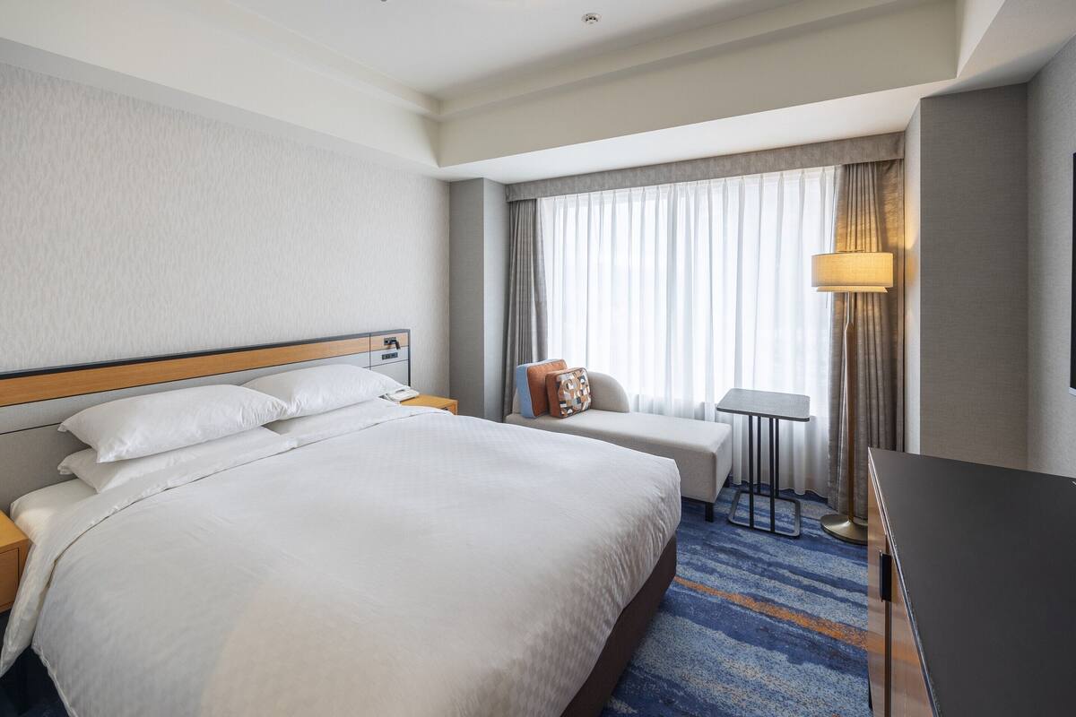 Habitación de hotel con una cama grande, una mesita, una silla y un escritorio.
