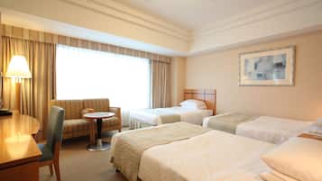 A hotel room with two beds, a sofa, a small round table, and a lamp.