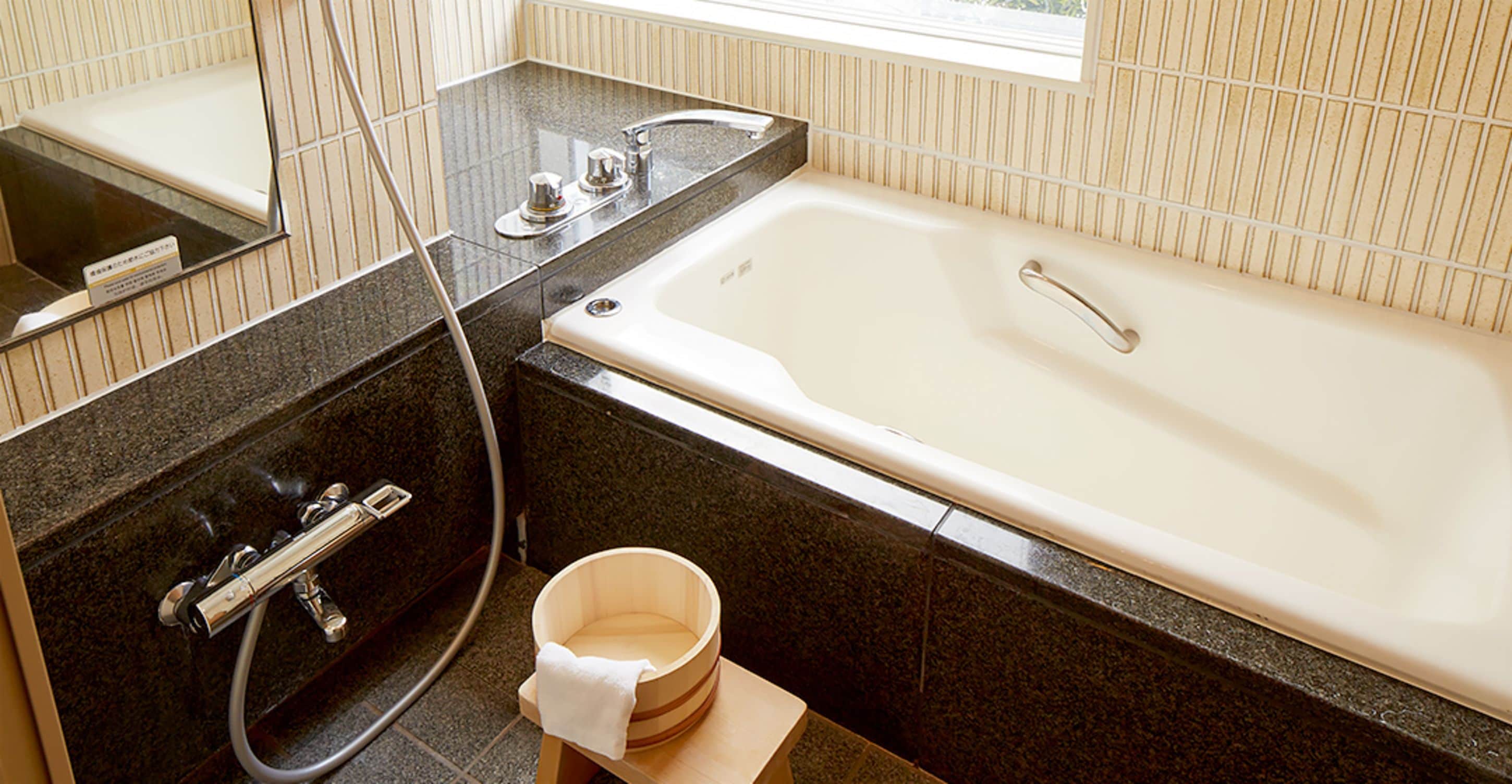 Un baño moderno con bañera, ducha y un cubo de madera.