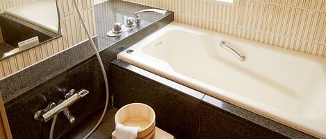 Un baño moderno con bañera, ducha y un cubo de madera.