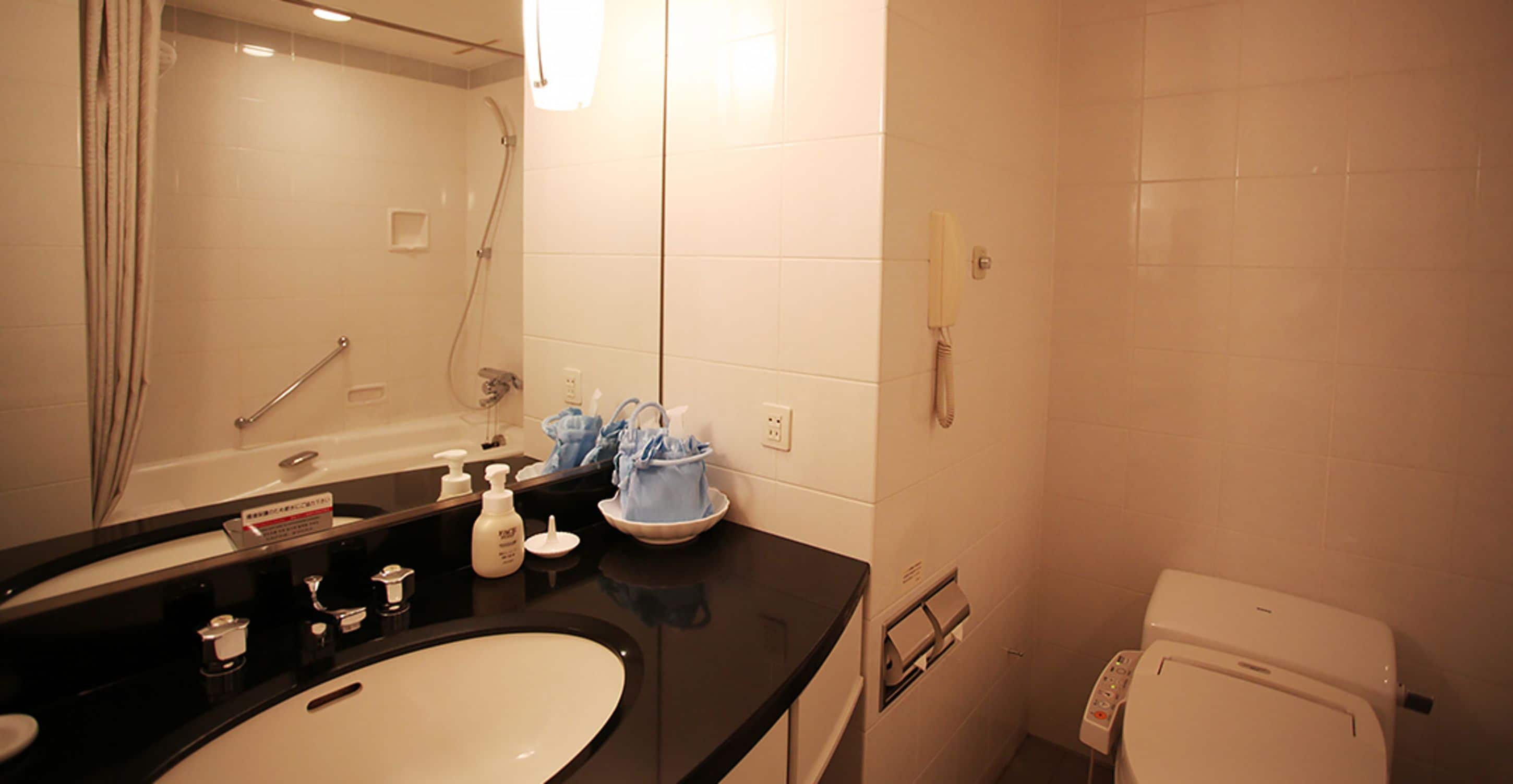 A bathroom with a sink, mirror, shower, and toilet.