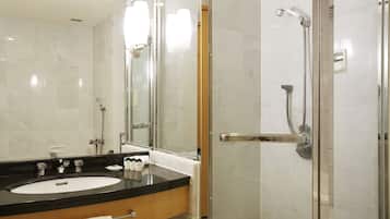 Un baño moderno con ducha de vidrio, lavamanos de superficie negra y un espejo grande.