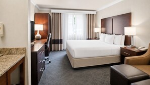A hotel room with a bed, desk, chair, and a view of the outdoors. - Comfort Inn Columbia Gorge (The Dalles)