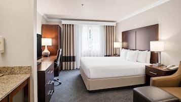 Una habitación de hotel con cama, escritorio, silla y un pequeño rincón de descanso.