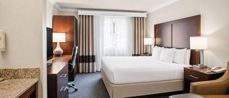 Een hotelkamer met een bed, bureau, stoel en een klein zithoekje.