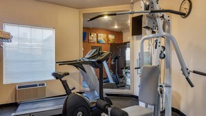 A gym with a treadmill, weight machine, and a mirror reflecting the interior. - Comfort Inn Columbia Gorge (The Dalles)