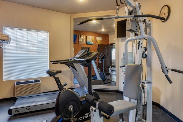 A gym with a treadmill, weight machine, and a mirror reflecting the interior. - Comfort Inn Columbia Gorge (The Dalles)
