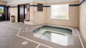 Area benessere con vasca idromassaggio, cestino e cartello con indicazioni sull'uso della spa.