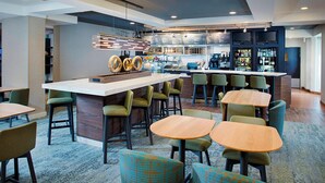 A modern hotel lobby with a bar area, seating arrangements, and a visible counter. - Courtyard by Marriott West Palm Beach Airport (West Palm Beach)