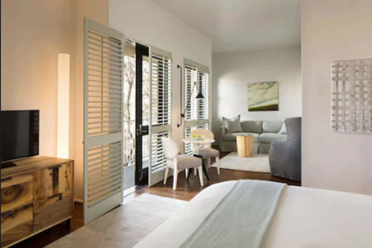 A hotel room with a bed, a desk, a chair, a television, and a window with blinds.