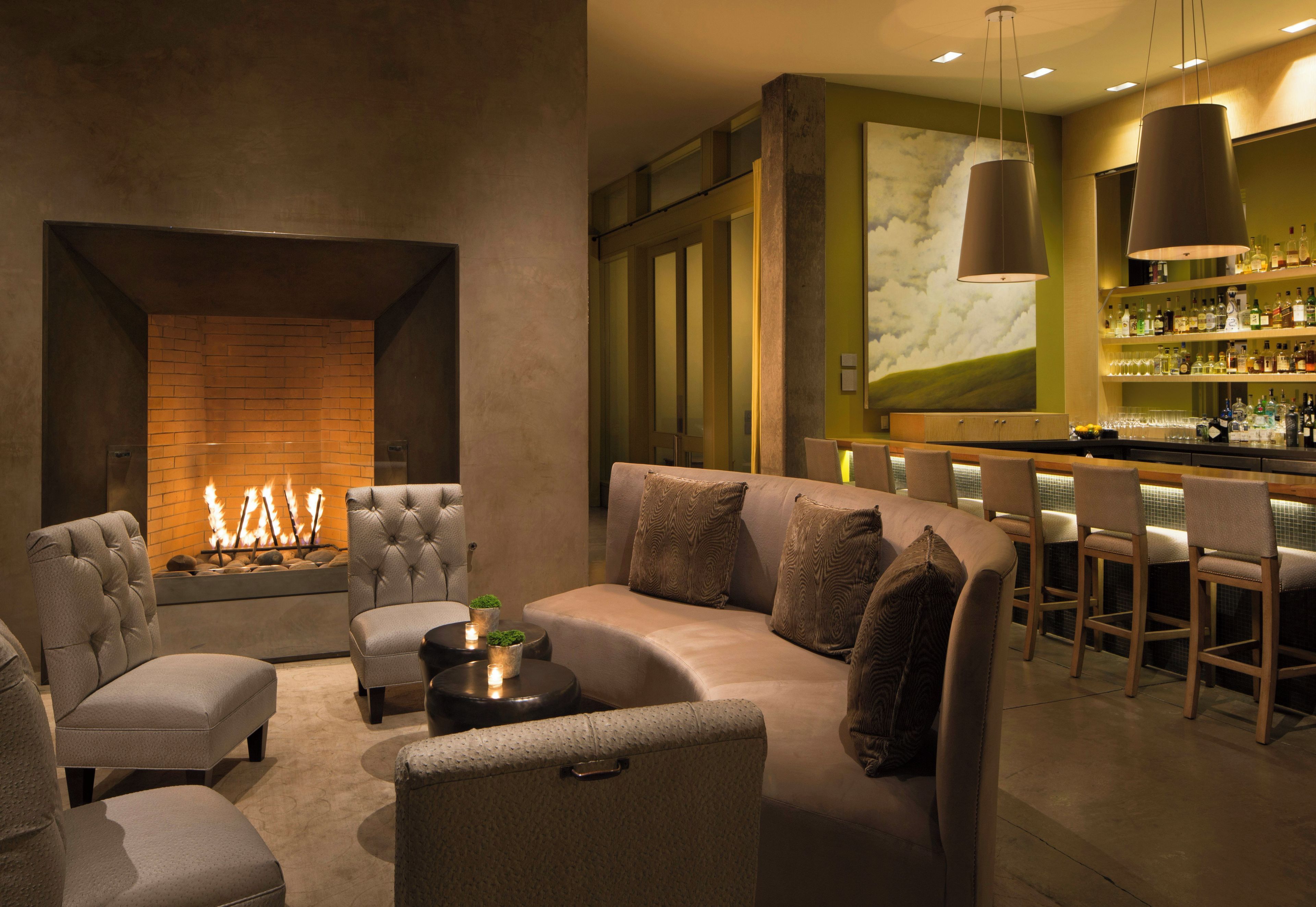 A modern lounge area with a fireplace, comfortable seating, and a bar with a variety of bottles.