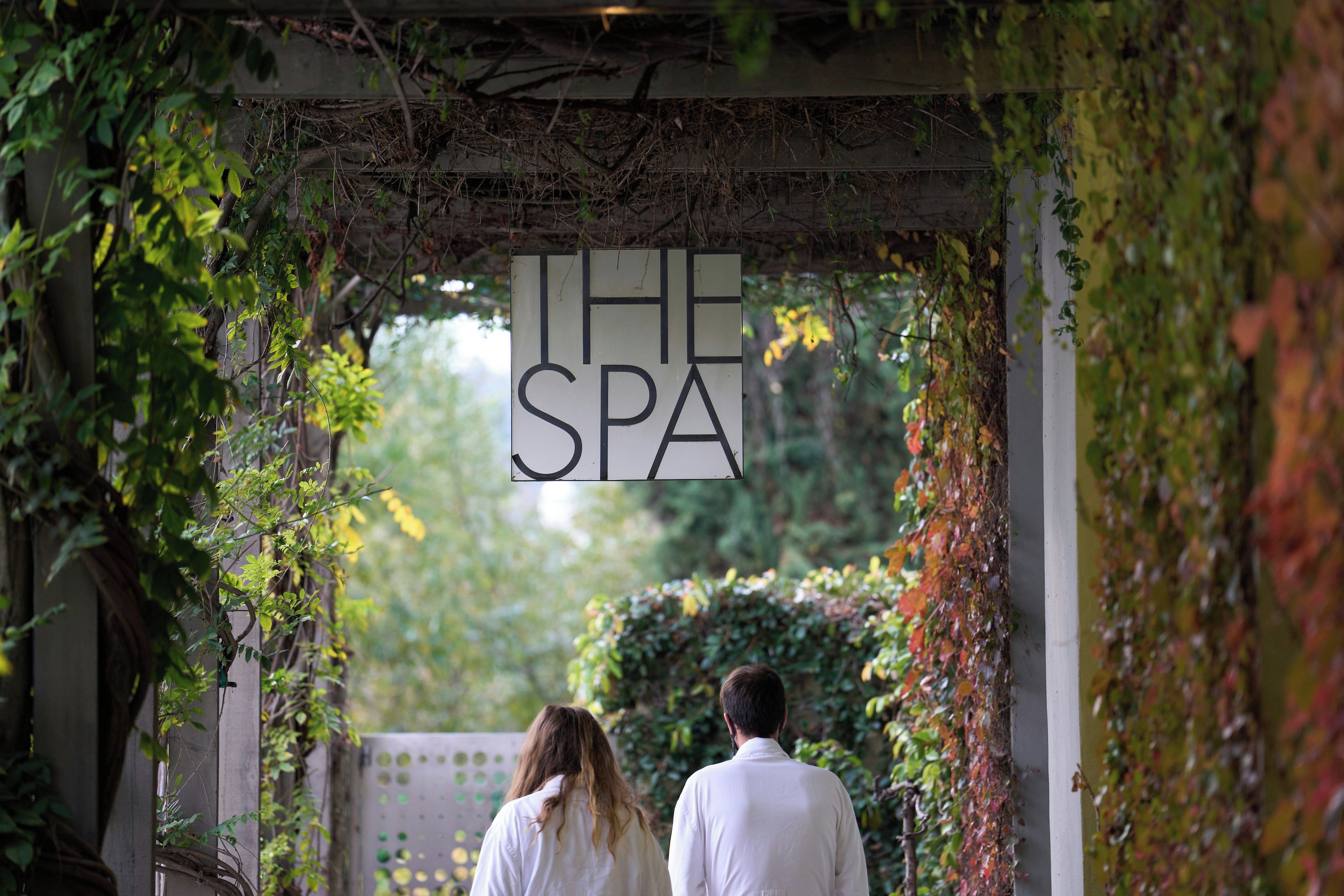 A pathway leading to a sign that reads 'THE SPA' with greenery on either side.