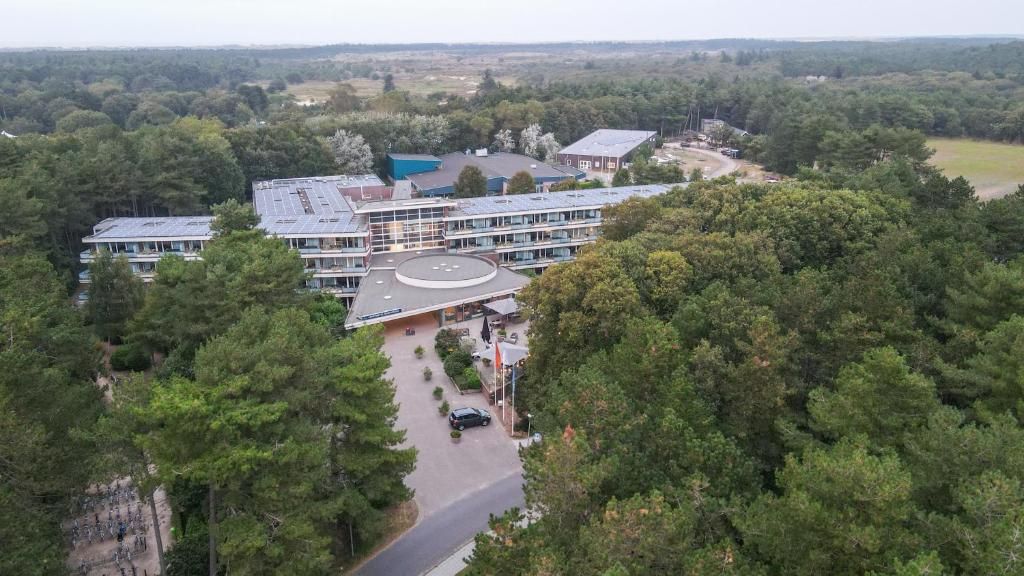 A multi-story building with a central courtyard, surrounded by dense forest.