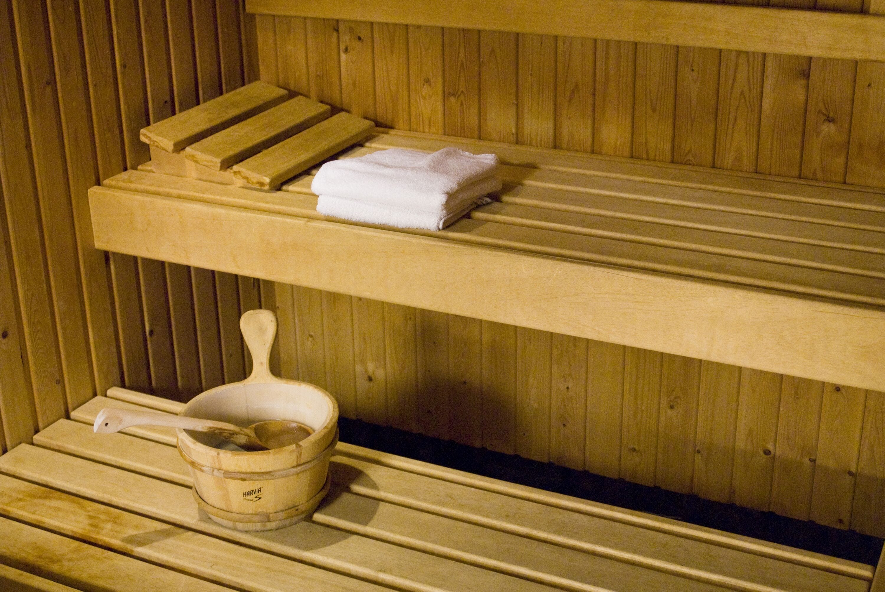 A wooden sauna with benches and a wooden bucket with a ladle.