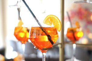 Um close-up de um copo de cocktail com uma fatia de laranja e um canudo.