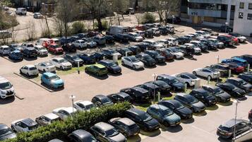 A large parking lot with numerous cars, surrounded by buildings and trees.