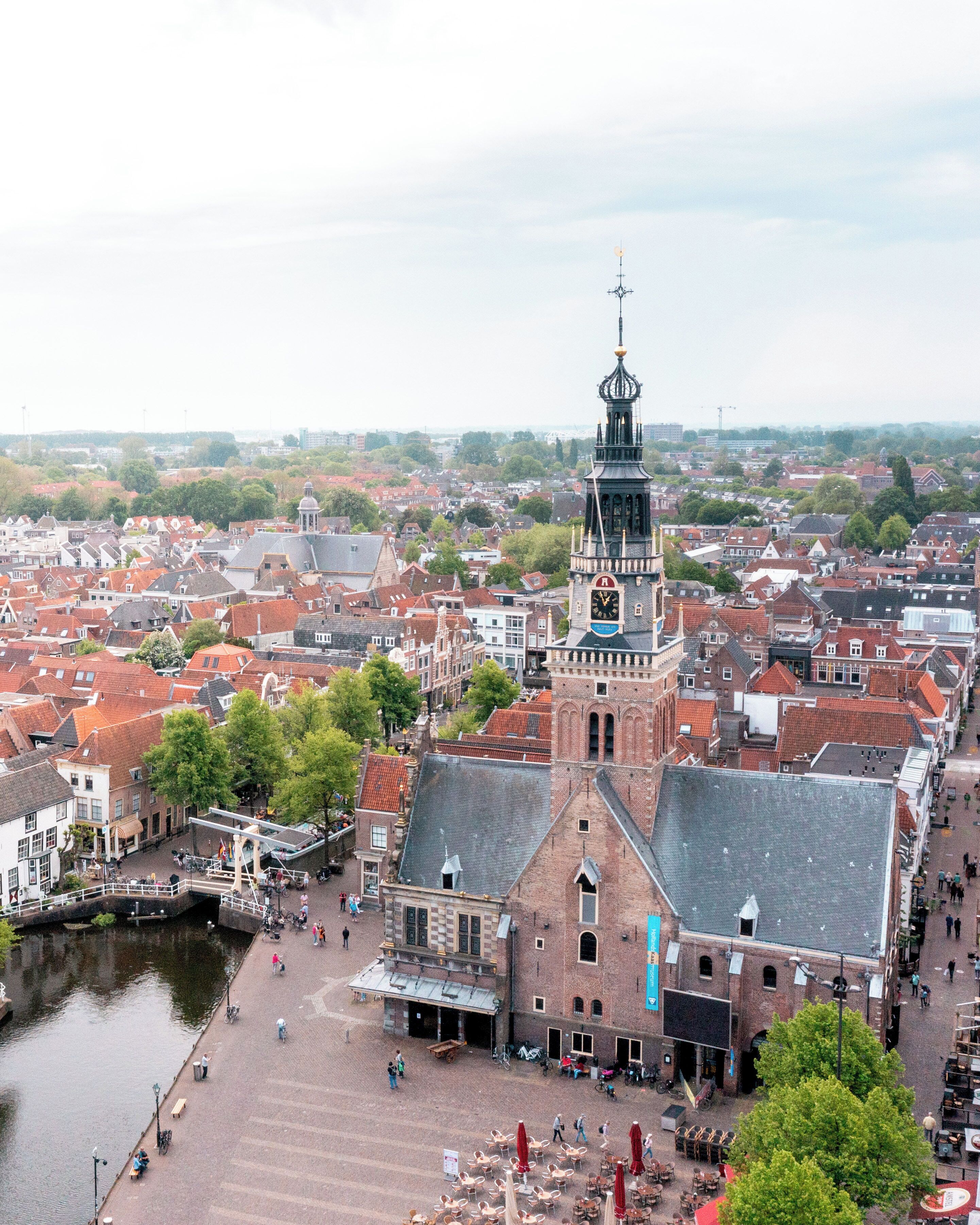 A historic town with a prominent clock tower, a canal, and a pedestrian area with outdoor seating.