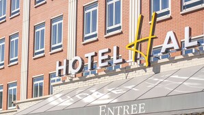 Entrada de hotel com área de estar coberta e porta de vidro.