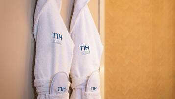 Two white robes with "NH Hotels & Resorts" branding hanging on a wall.