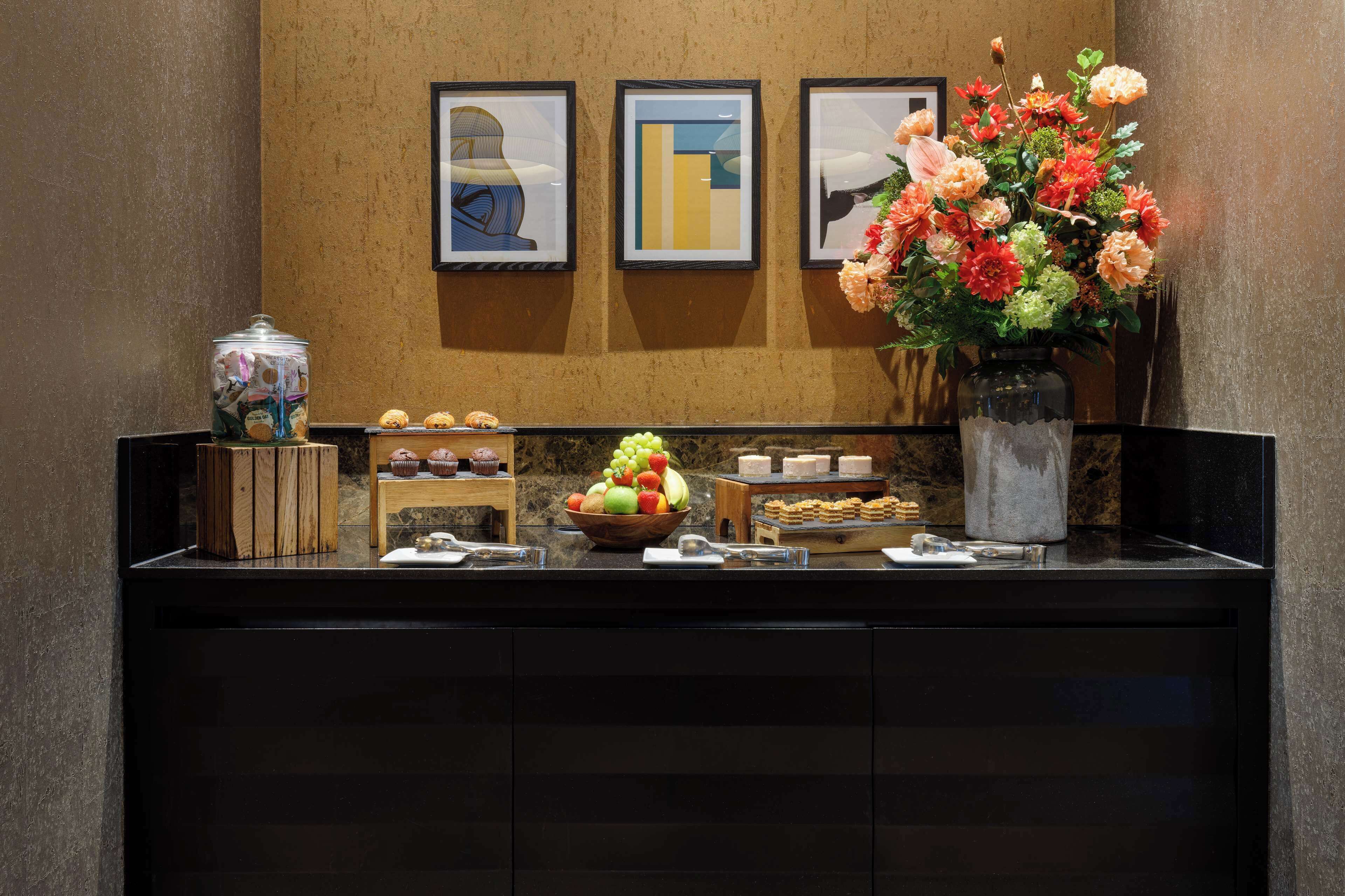 A reception area with a counter displaying a fruit bowl, a vase with flowers, and framed artwork on the wall.