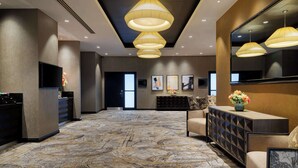 A hotel lobby with a patterned carpet, a reception desk, a sofa, and pendant lighting. - Doubletree by Hilton Hotel Woking (Woking)