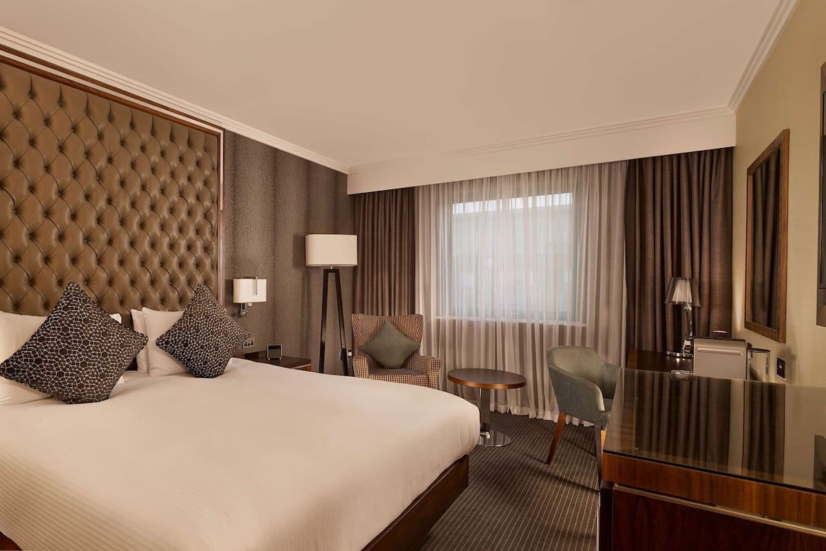 Habitación de hotel con una cama grande, un televisor de pantalla plana, un escritorio y una silla.