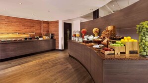 A modern kitchen with a wooden backsplash, a built-in coffee station, and a variety of fruits and vegetables on the counter. - Doubletree by Hilton Hotel Woking (Woking)