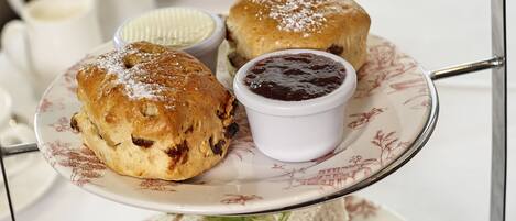 Uma bandeja escalonada com diversos doces e sobremesas, incluindo scones, sanduíches e macarons.