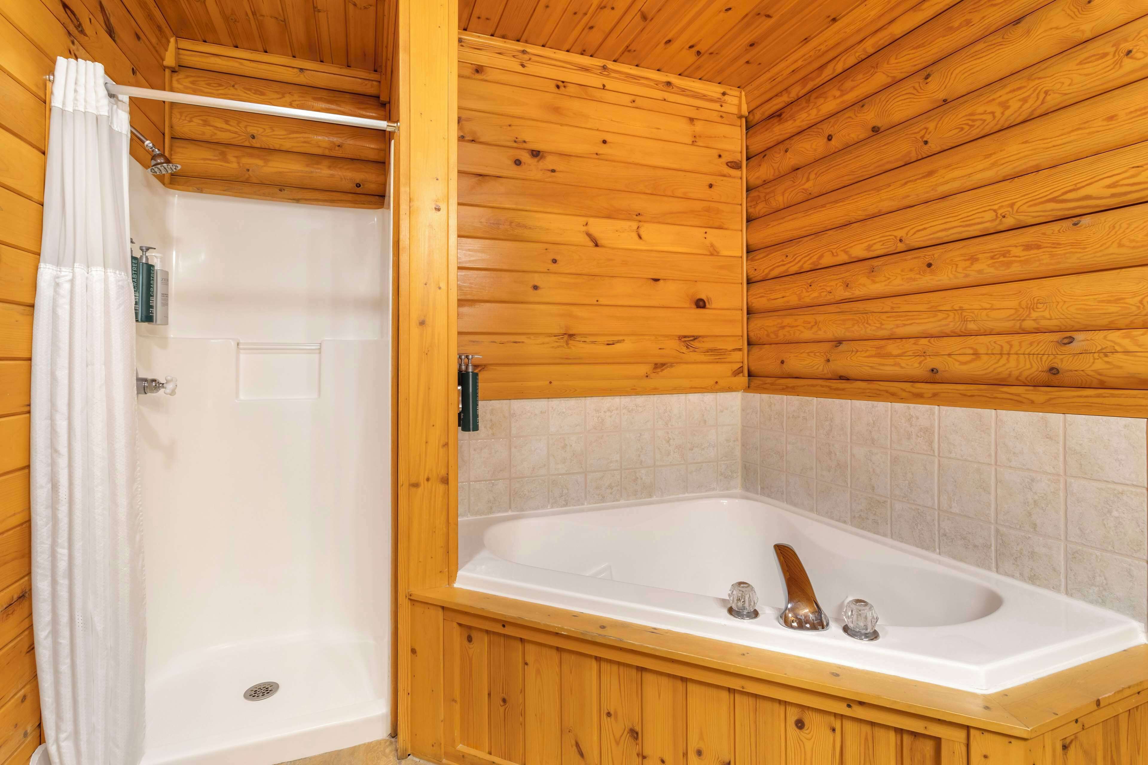Een badkamer met houten lambrisering, een bad en een douche.