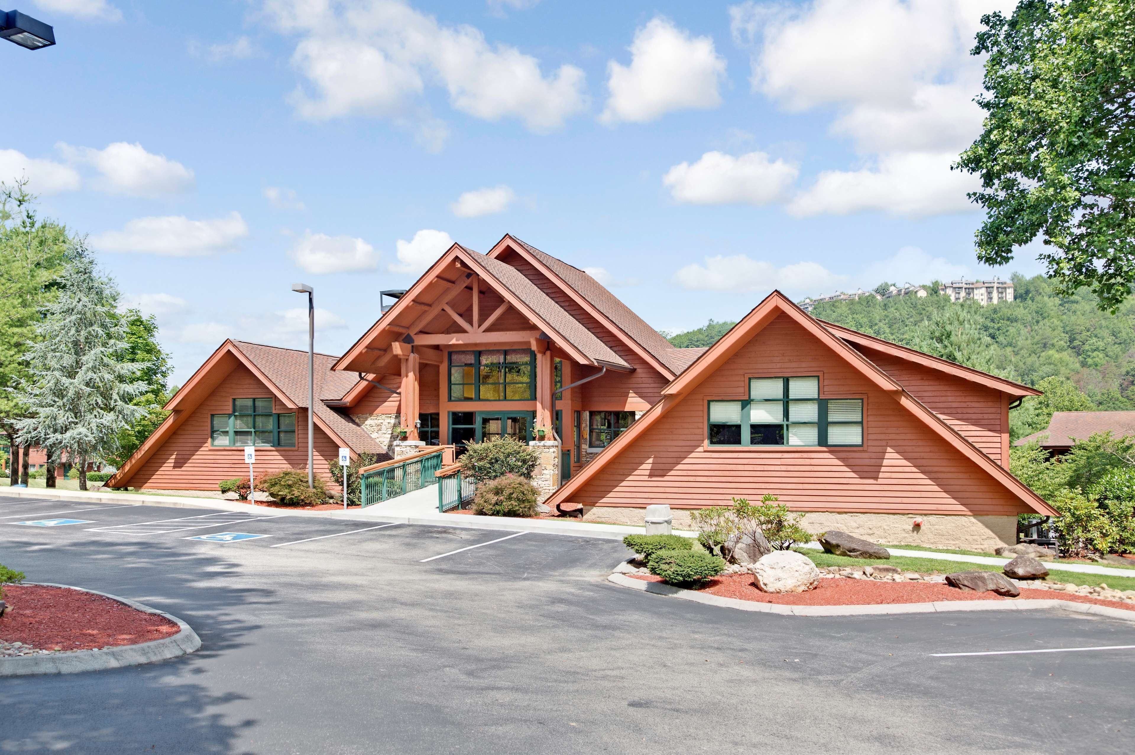 A lodge with a central entrance, multiple windows, and a parking lot.