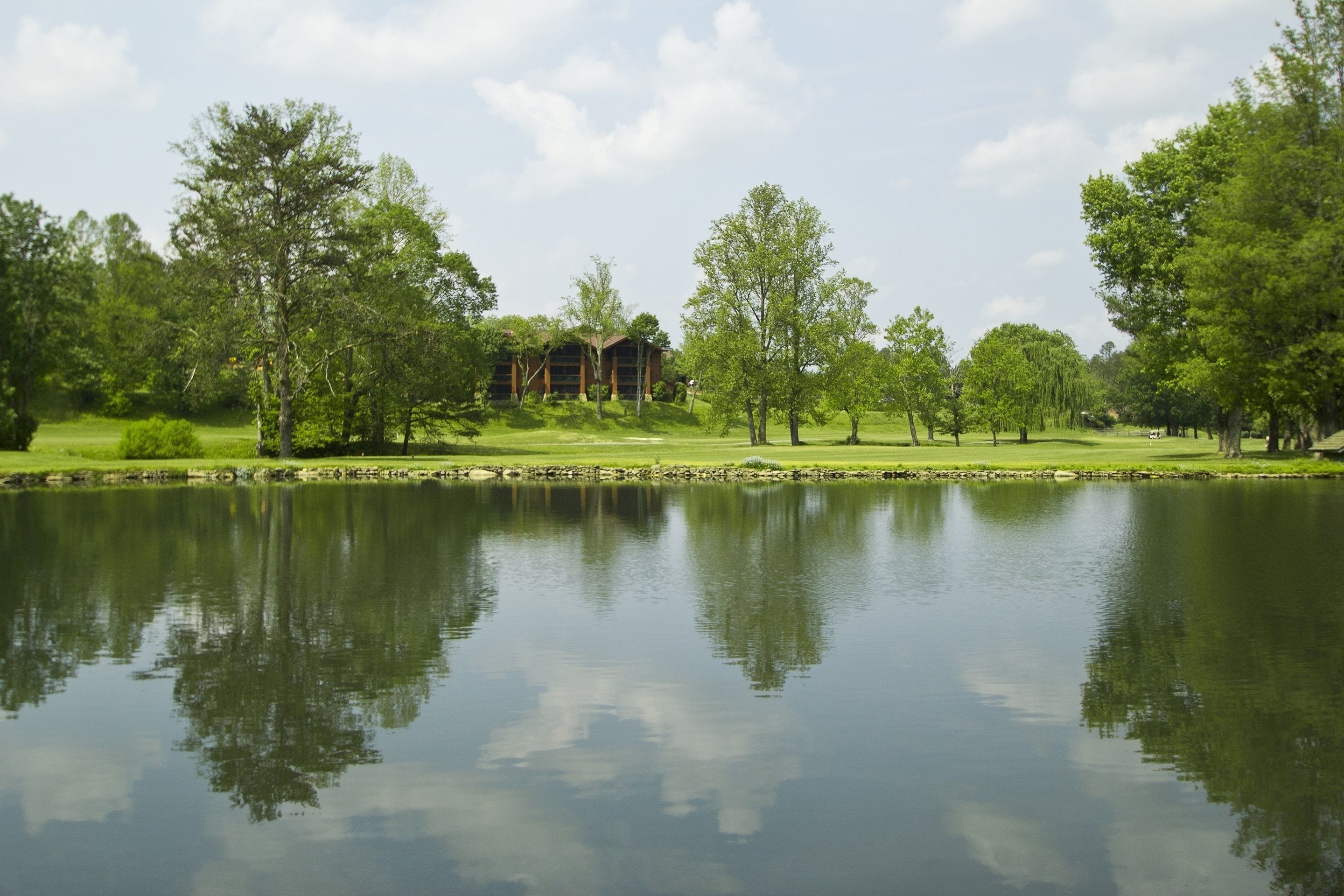 A tranquil lakeside setting with a building surrounded by lush greenery and trees.
