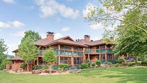 A large, multi-story house with a brick exterior, multiple balconies, and a well-maintained lawn.