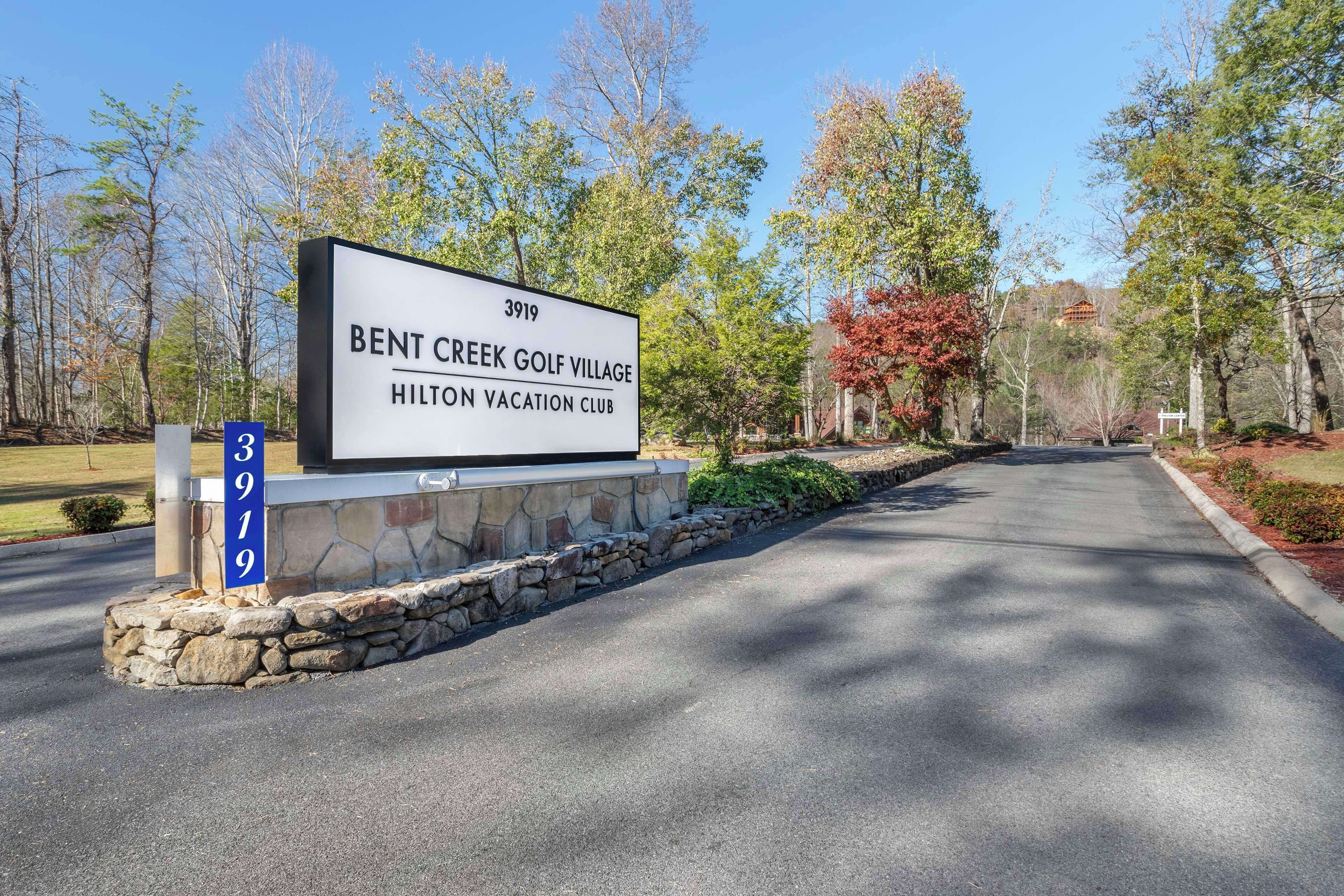 Señal de Bent Creek Golf Village, Hilton Vacation Club, con base de piedra y cartel azul.