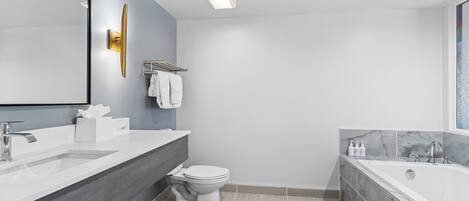 A modern bathroom with a large mirror, a sink, a toilet, and a bathtub.