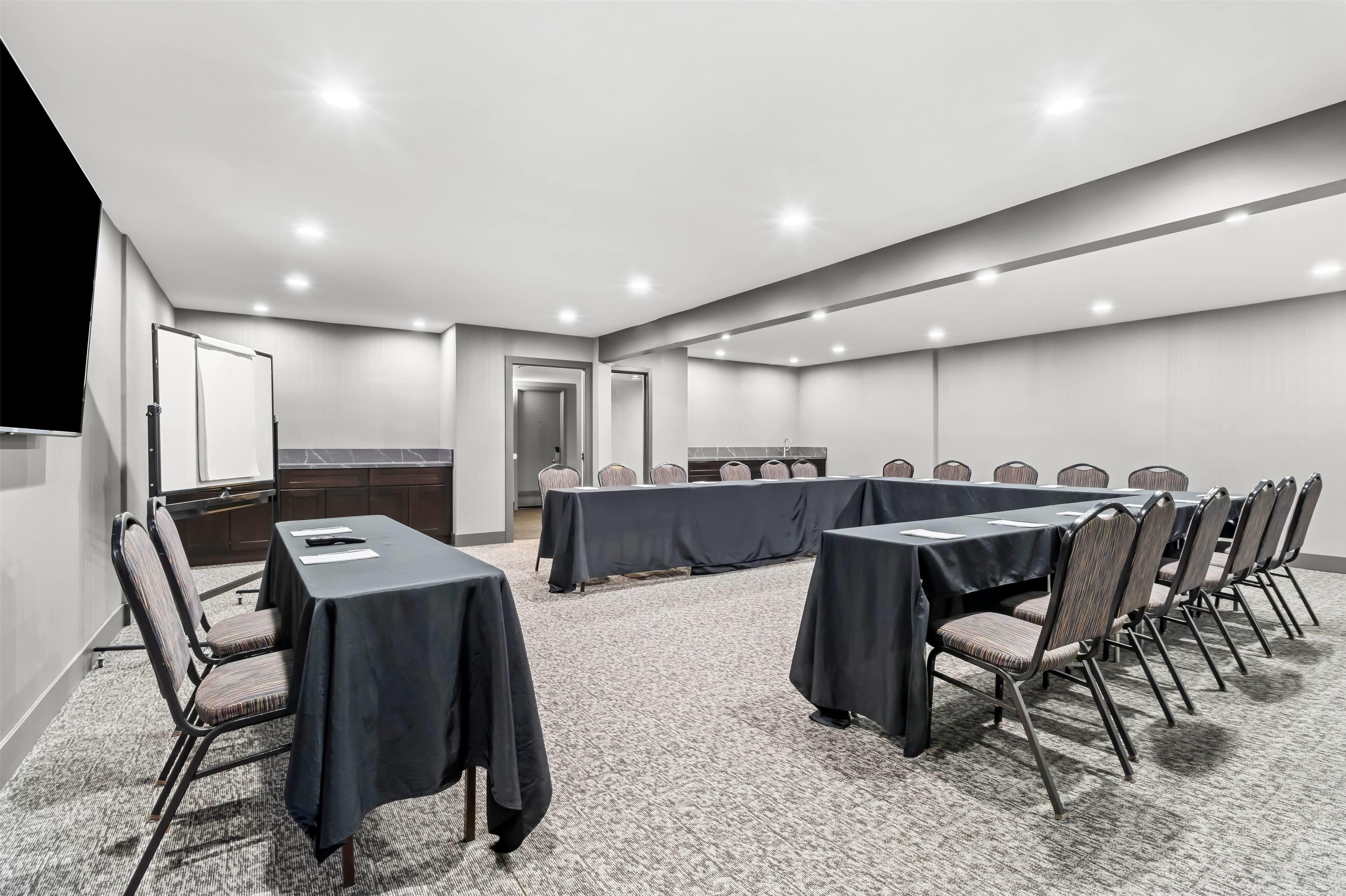 A conference room with a long table, chairs, and a whiteboard.