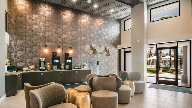 A modern lobby with a reception desk, seating area, and large windows offering a view of the outdoors.