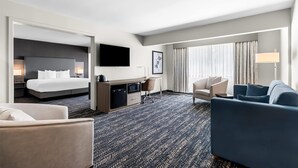 A hotel room with a bed, a desk, a TV, a sofa, and a chair.