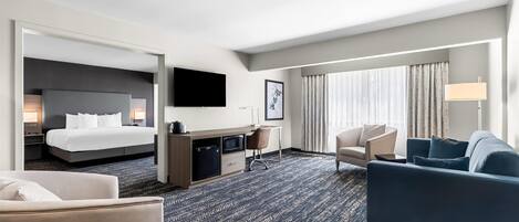 A hotel room with a bed, a desk, a TV, a sofa, and a chair.
