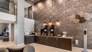 A modern reception area with a dark wood wall, a reception desk, and a coffee station.