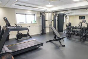 A gym with treadmills, weight machines, and dumbbells.